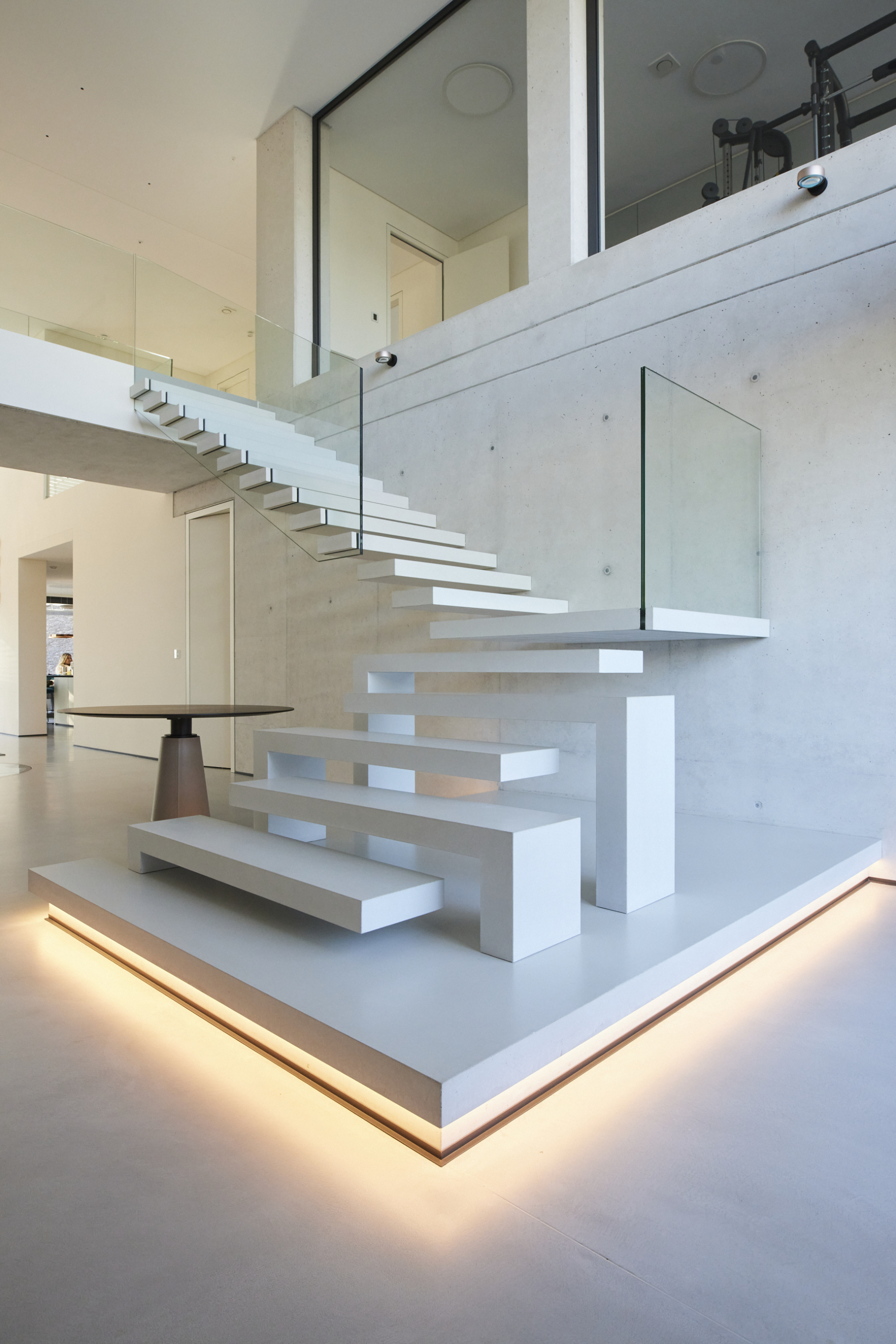 Material: Beton System: Stairs Fix Farbe: natura weiß Wand: Sichtbeton Geländer: Glasscheibe Sonstiges: LED-Beleuchtung, Podest